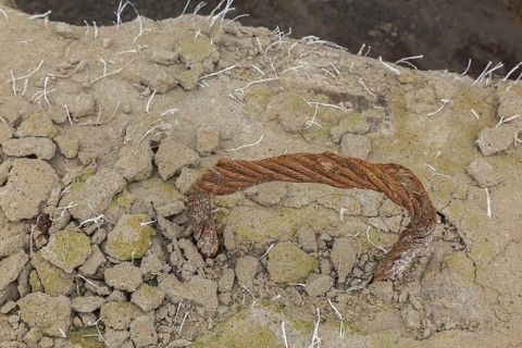 Handle shaped rusted steel cable encased in crumbling concrete block