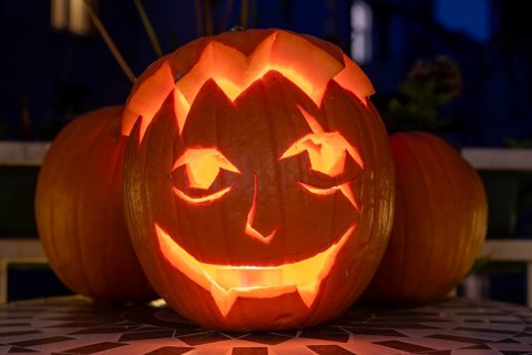 Carved pumpkin stands on a balcony on Halloween evening