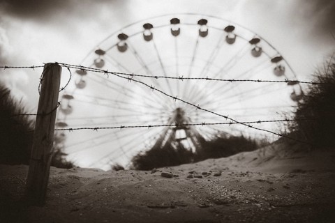 Ferris wheel behind barbed wire on the beach of De Panne