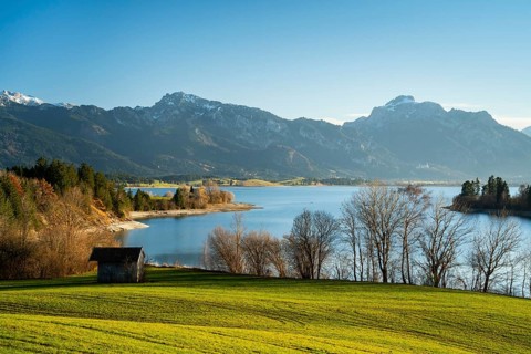 The Illasbergsee in the Allgäu in autumn in the late afternoon in good weather with a blue sky. A small hut in the foreground