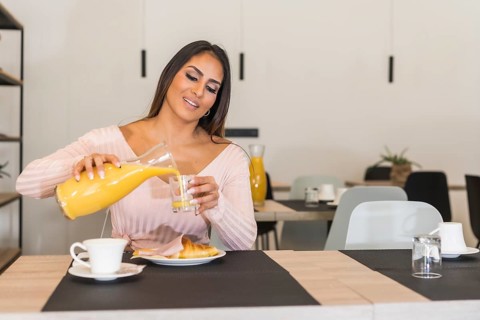 Horizontal portrait of a casual businesswoman drinking orange juice during breakfast in an hotel