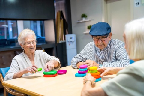 Three cute elder people playing skill games together in a nursing home
