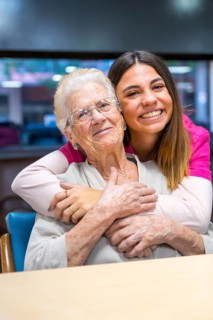 Vertical portrait of a cute nurse and an elder woman in a geriatric
