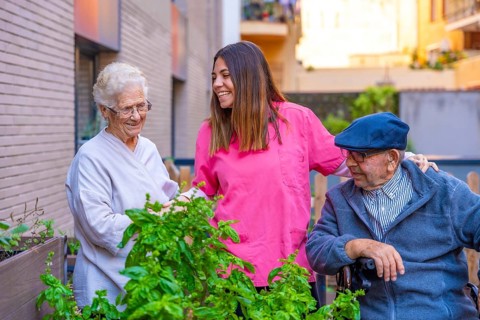 Nurse chatting with elder people in a vegetable garden in a geriatric