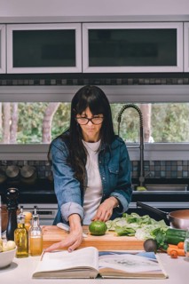 Woman reading recipe while preparing food in the kitchen. Vertical shot. Copy space