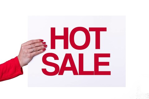Woman hand holding a HOT SALE white poster on transparent background. Studio shot. Commercial concept