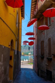City Street in Porto Ceresio with Hanging Umbrellas with Lake View in a Sunny Summer Day in Porto Ceresio
