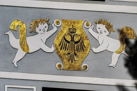 Fresco with golden coat of arms and double-headed eagle with crown on grey facade