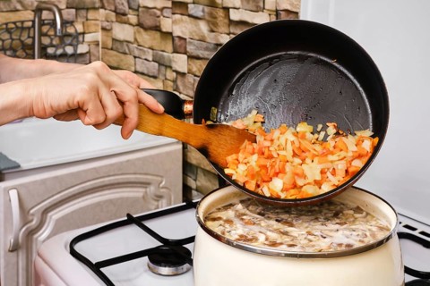 Unrecognizable woman adding fried carrot
