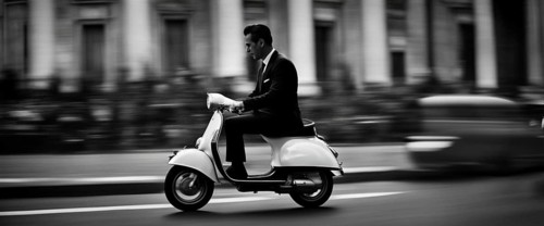 Italian elegant man wearing suit and tie driving moped vintage scooter in Rome Italy at sunset traditional urban scene