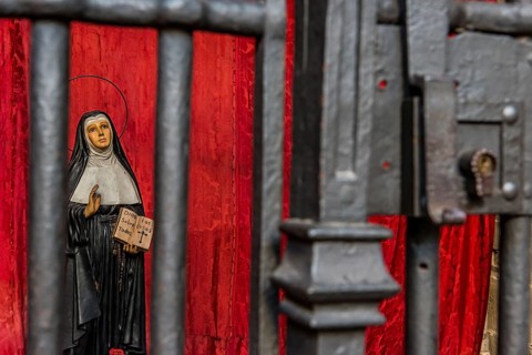 Model of a praying nun behind bars