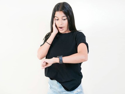 Surprised young woman looking at wrist watch. Worried young woman looking at her watch isolated