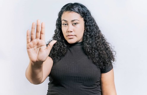 Close up of woman gesturing stop with the palm of hand isolated. People gesturing stop isolated. Latin woman gesturing stop with palm hand isolated