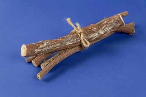 Pile of licorice roots tied with a rope isolated on a blue background