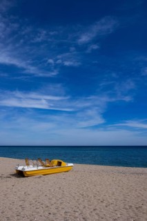 Yellow pedal boat on the beach with blue sky and blue sea