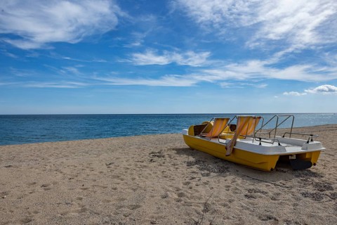 Yellow pedal boat on the beach with blue sky and blue sea