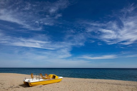 Yellow pedal boat on the beach with blue sky and blue sea
