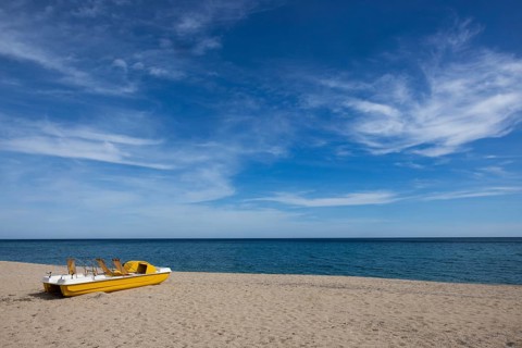 Yellow pedal boat on the beach with blue sky and blue sea