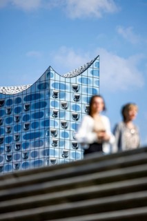 Silhouettes of people on the harbour promenade in front of the Elbe Philharmonic Hall