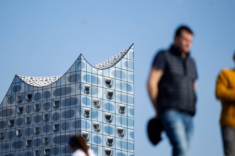 Silhouettes of people on the harbour promenade in front of the Elbe Philharmonic Hall
