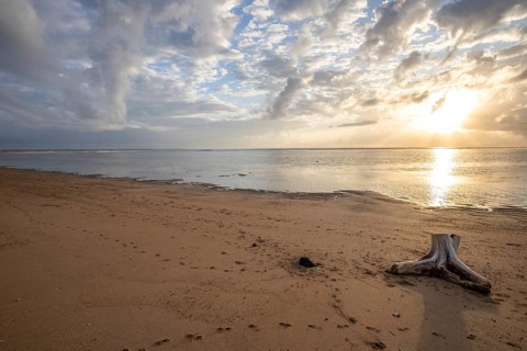 Sunrise on the sandy beach. Landscape shot with a view of the sea and the beach. Waves of light and a morning atmosphere that only exists in Sanur