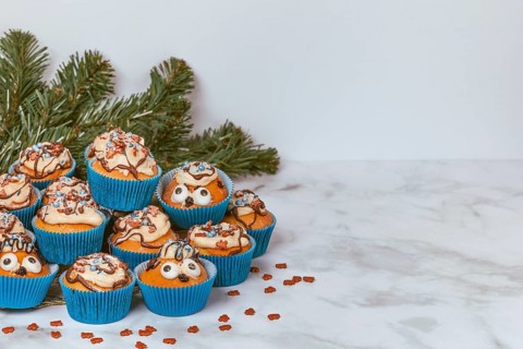 Muffins in blue ramekins with chocolate icing and sugar sprinkles