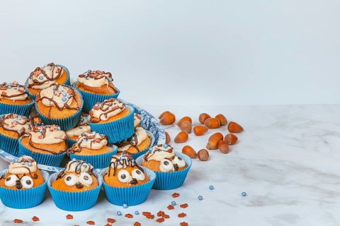 Muffins in blue ramekins with chocolate icing and sugar sprinkles