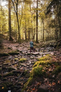 Woman standing on stones in the river autumn forest