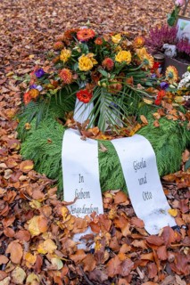 Flower wreath with mourning bows on autumn leaves at a memorial tree with the names of those buried there in Seelwald