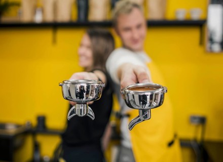 Baristas posing back back while holding cups