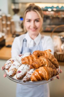 Blurred young woman offering croissants glass cake stand