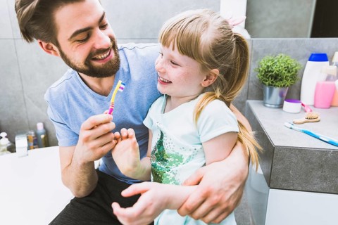 Cheerful father daughter brushing teeth