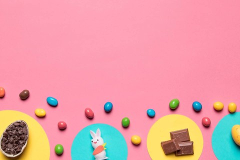 Choco chips rabbit statue chocolate pieces colorful candies pink backdrop with space text