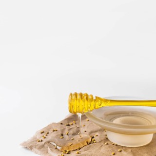 Close up sweet honey dripping from dipper with bee pollen seeds brown paper