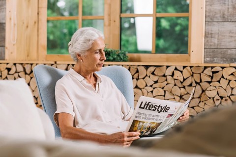 Close up woman sitting chair reading newspaper