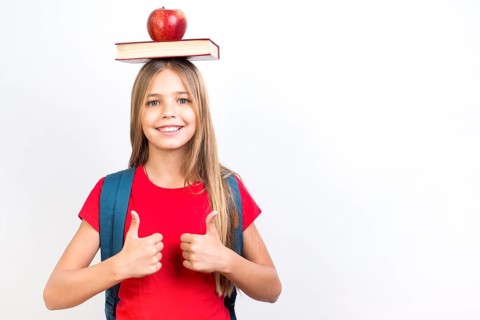 Confident schoolgirl balancing book head