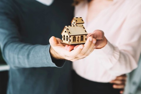 Crop couple holding toy house