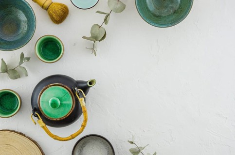 Elevated view teapot bowl tea cup brush isolated white backdrop