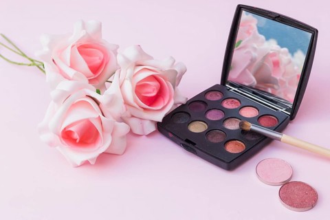 Fake pink flowers with blusher eyeshadow palette with makeup brush