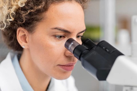 Female researcher laboratory looking through microscope