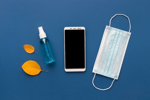 Flat lay medical mask with smartphone hand sanitizer