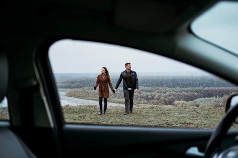 Front view couple holding hands from inside car