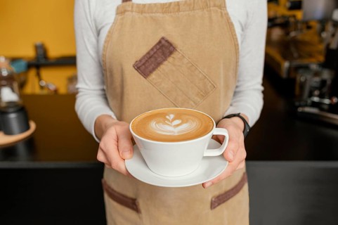 Front view female barista holding decorated cup coffee hands
