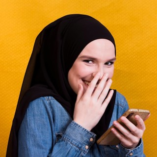 Happy woman wearing denim shirt using smartphone bright background
