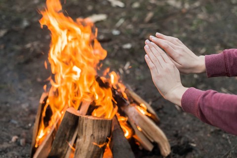 High angle woman warming bonfire