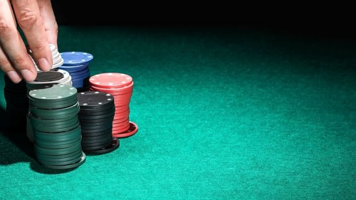 Human hand with casino chips green table
