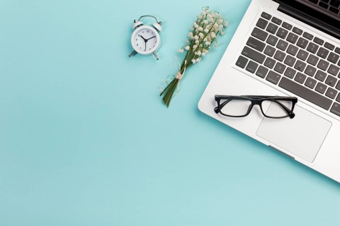 Lily valley bouquet with alarm clock eyeglasses laptop blue office desk