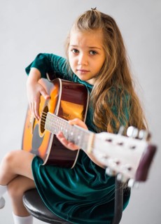 Little girl dress playing acoustic guitar