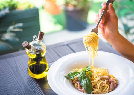 Olive oil bottle with person holding spaghetti with fork