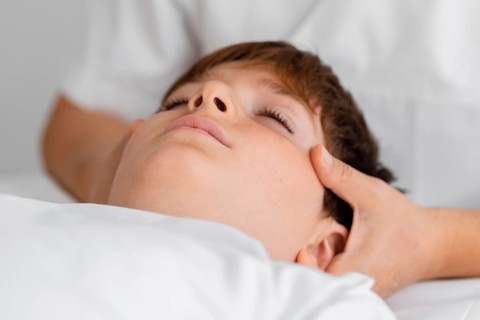 Osteopathist treating child by massaging his head